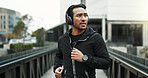 Fitness, man and running with headphones in city for workout, pace training and cardio playlist. Athlete, person and streaming music on bridge for endurance challenge, morning exercise or performance