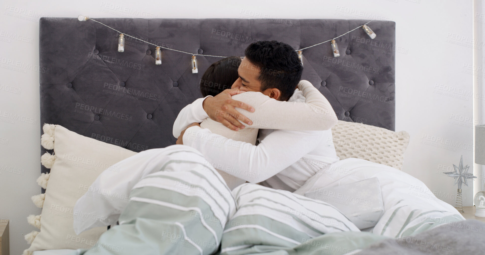 Buy stock photo Christmas, couple and hug in bed with gift for holiday tradition, connection and appreciation in home. Married people, present and embrace in house for festive season, gratitude and bonding together.