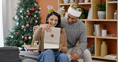 Buy stock photo Christmas, couple and happy in living room with gift for holiday tradition, connection and gratitude. Married people, smile and present in house for festive season, appreciation and bonding together.