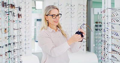 Buy stock photo Vision, woman and cleaning glasses in shop, eye care and maintenance of stock with smile. Store, wipe eyewear and mature person with cloth fabric for frame, optometrist and spectacles for health
