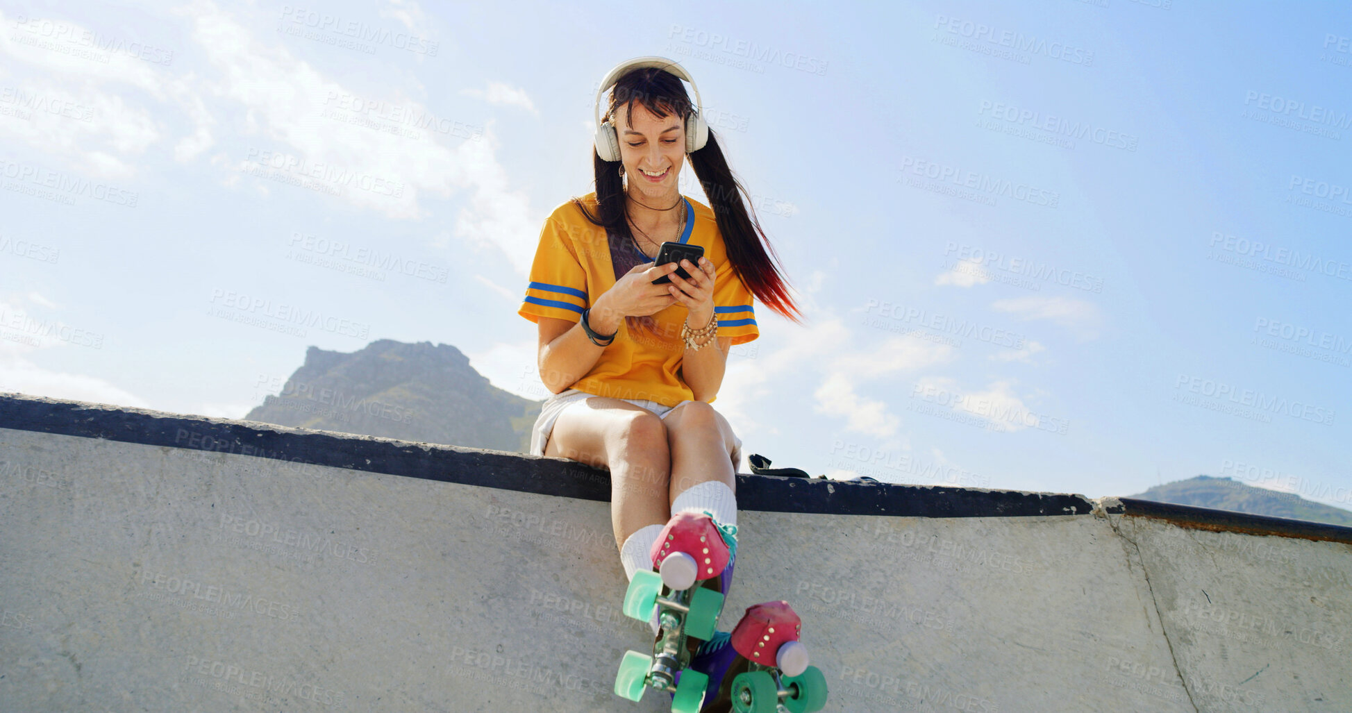 Buy stock photo Happy woman, headphones or phone with roller skates for audio streaming, playlist or outdoor hobby. Low angle, female person or hipster with mobile smartphone or music for entertainment on legde