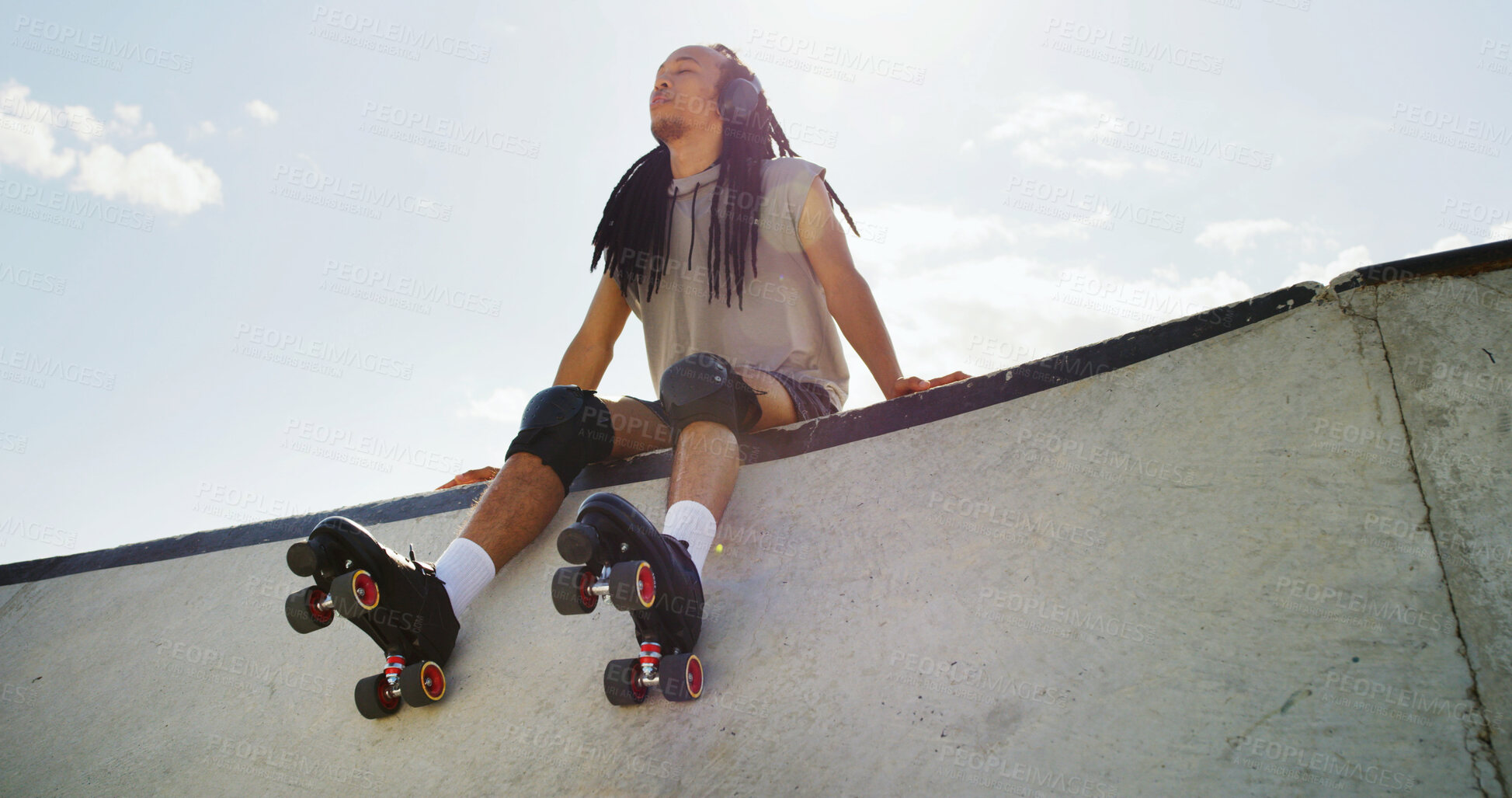 Buy stock photo Man, roller skates and relax at park with headphones, low angle or listen to music with space in city. African person, skater and break for streaming subscription, audio or rest on ramp in urban town