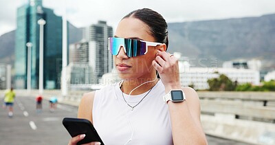 Buy stock photo Woman, runner and phone with earphones in city, bridge and audio subscription for training. Person, smartphone and sunglasses with mobile app, listen and streaming music with fitness in urban street
