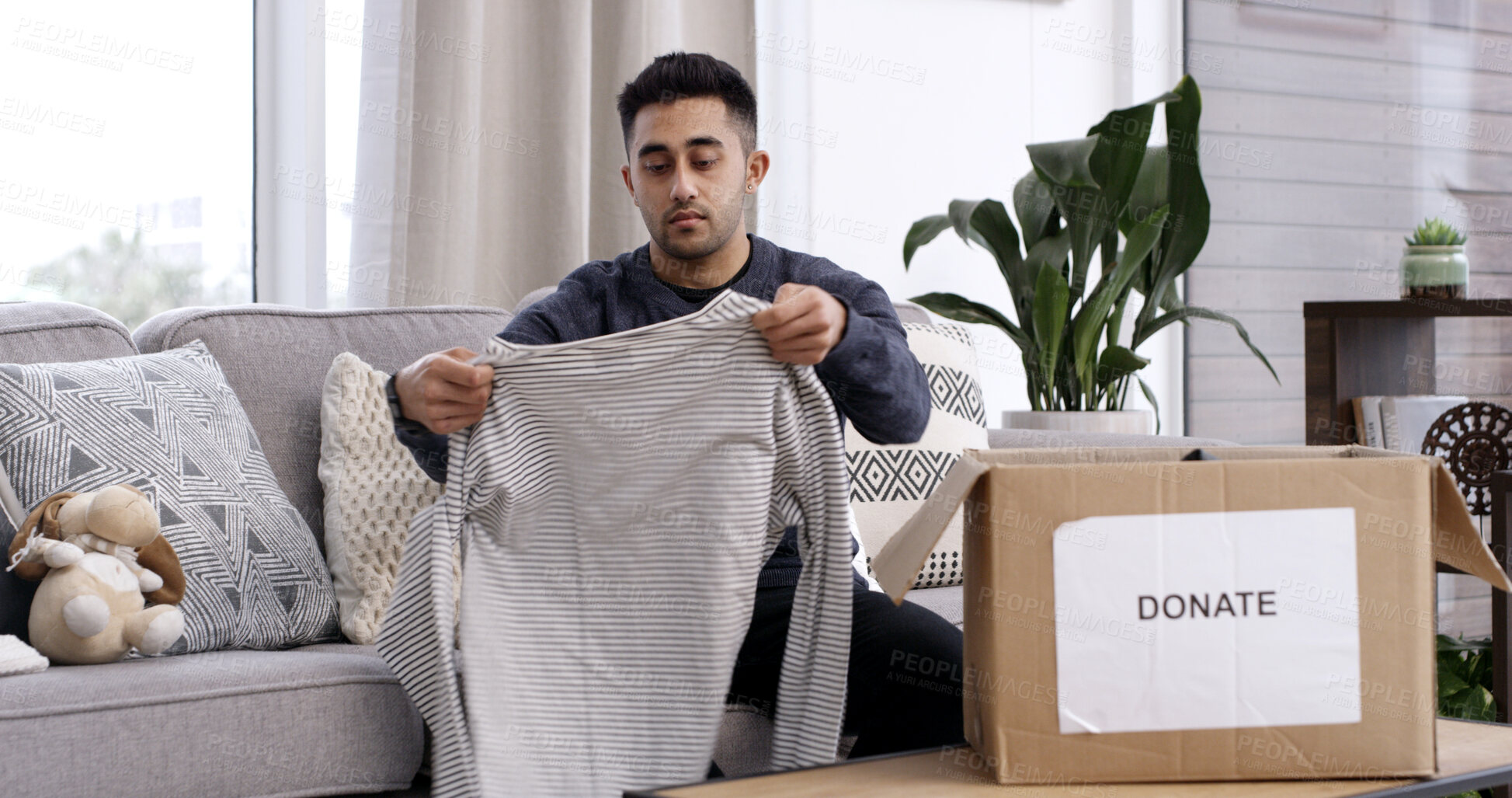Buy stock photo Man, folding clothes and donation box in house for charity initiative, nonprofit and declutter closet. Person, package and apparel giveaway in home for NGO contribution, support and spring cleaning.