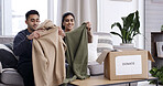 Couple, folding clothes and donation box on sofa for charity initiative, nonprofit or declutter home. Married people, apparel giveaway and package in house for NGO support, parcel or spring cleaning.