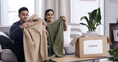 Buy stock photo Couple, folding clothes and donation box on sofa for charity initiative, nonprofit or declutter home. Married people, apparel giveaway and package in house for NGO support, parcel or spring cleaning.