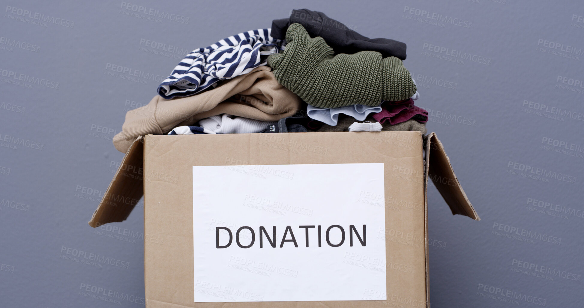 Buy stock photo Clothes, charity and donation box in studio for non profit, humanitarian aid or support package. Cardboard, garments and community care with outreach, ngo or help for philanthropy on gray background