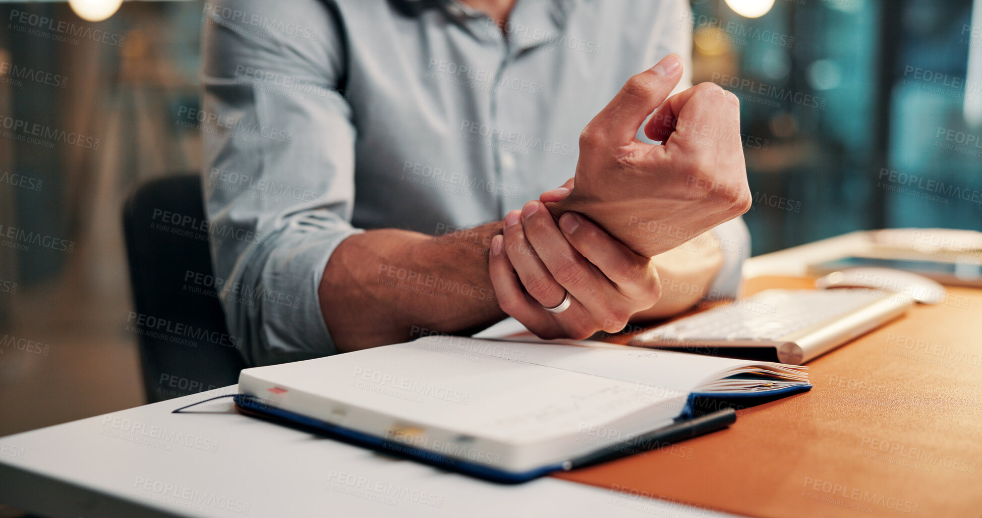 Buy stock photo Wrist pain, night or hands in office with notebook, burnout or joint inflammation in carpal tunnel. Ache, man and employee in agency with writing, muscle tendinitis or arthritis in overtime work.