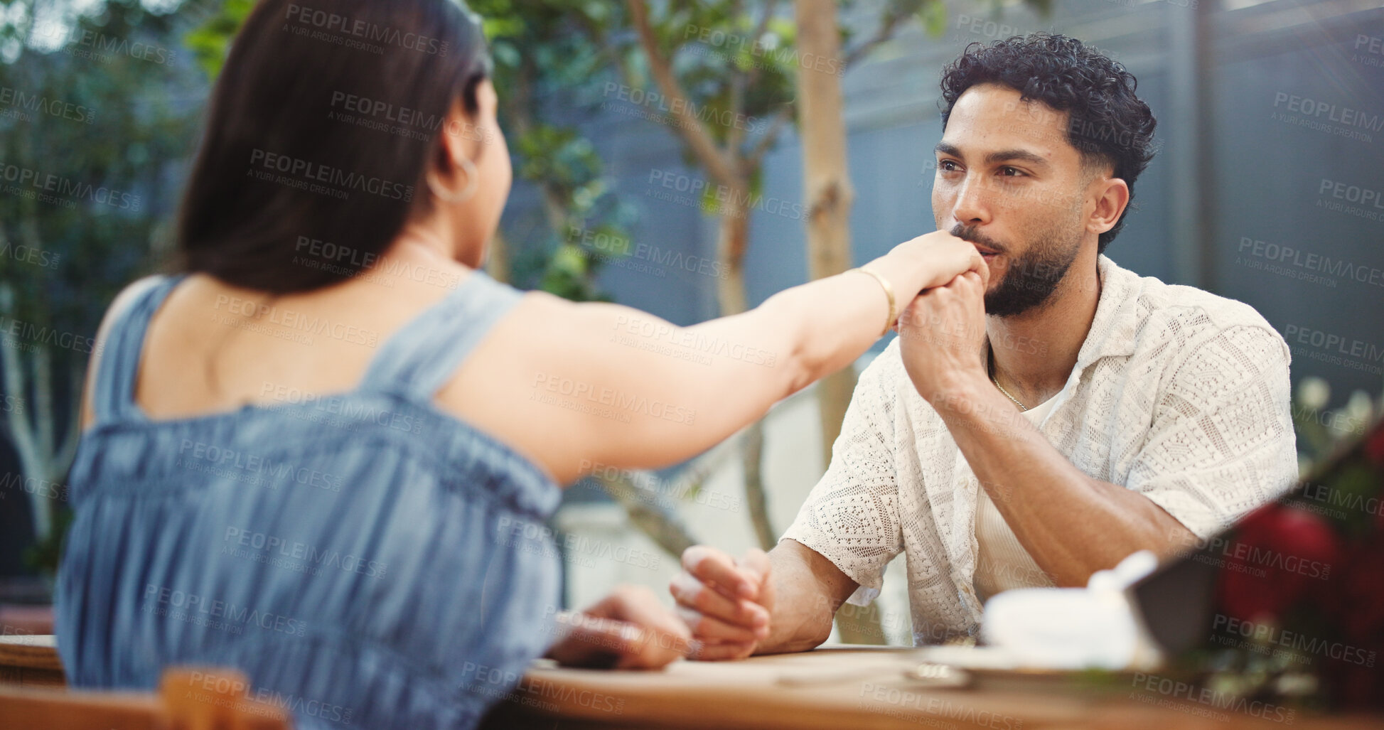 Buy stock photo Couple, holding hands and kiss on date at restaurant with bouquet, discussion and relationship milestone. Happy man, woman and connection with bonding, trust and flowers for anniversary at diner