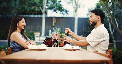 Buy stock photo Couple, champagne and talk on date at restaurant, excited and celebration for relationship milestone. Happy woman, man and open bottle for sparkling wine, smile or anniversary with flowers at diner