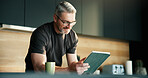 Glasses, remote work and tablet with man in kitchen of home for planning, report or research. App, reading and small business with mature freelancer in apartment for schedule or startup review