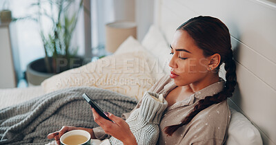 Buy stock photo Woman, phone and sick in bed with texting, herbal tea and hot water bottle for recovery in home. Person, smartphone and rest with drink for flu virus, mobile app or relax with chat on social media