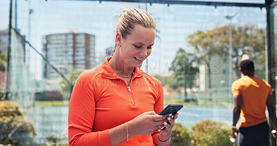 Buy stock photo Woman, phone and happy with texting at tennis court, fitness or break for web chat at urban park. Person, smartphone and notification on mobile app, social media or smile with training at sports club