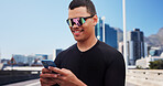 Man, runner and phone with texting in city, sunglasses and smile with fitness, notification and tracking. Person, happy and smartphone with mobile app, monitor or break for exercise on bridge in town