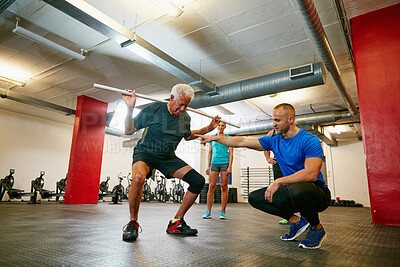 Buy stock photo Coach, old man or squat in gym class with pipe for mobility, fitness activity or exercise instructions. Personal trainer, senior person or pvc equipment with help for workout, stability or low angle.