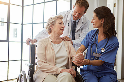 Buy stock photo Holding hands, medical team and senior woman in wheelchair for healing or healthcare conversation, Consulting, doctor and nurse talking to old person with disability in hospital for rehabilitation