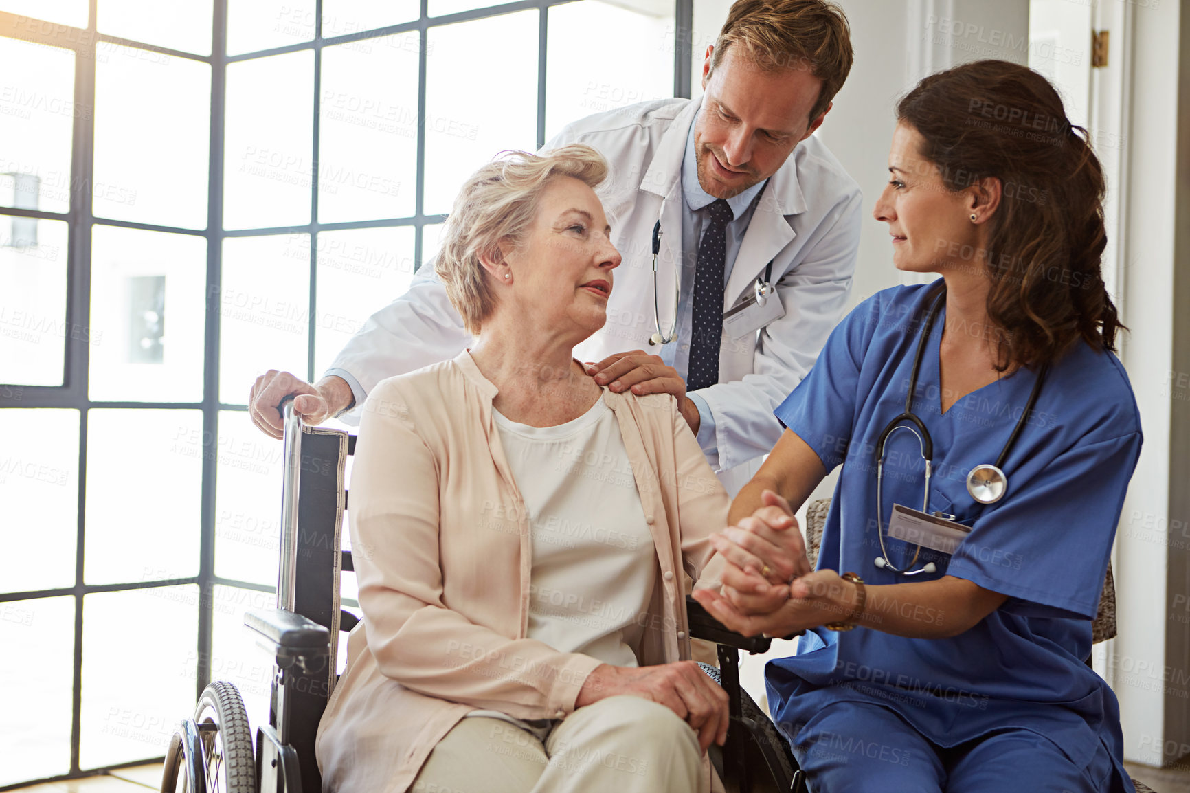 Buy stock photo Holding hands, medical team and senior woman in wheelchair for healing or healthcare conversation, Consulting, doctor and nurse talking to old person with disability in hospital for rehabilitation