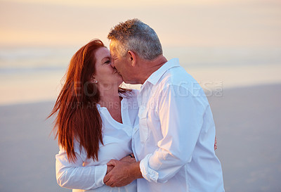 Buy stock photo Love, mature couple and kiss at beach for care, support and holding hands for connection on vacation. Man, woman and romance outdoor on holiday, travel or bonding together at sunset on valentines day