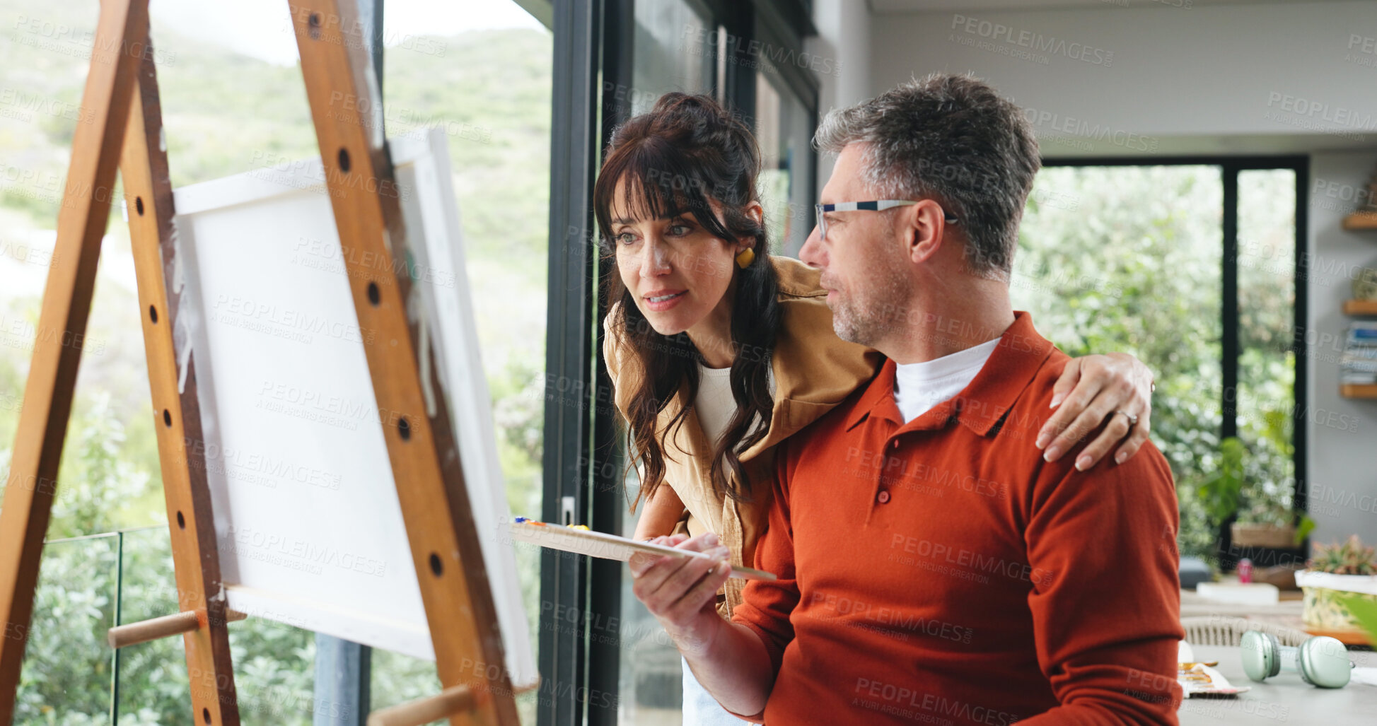 Buy stock photo Easel, couple and support with painting in home for creative activity, self expression and hug. Marriage, mature people or talking with canvas for custom art, exhibition project or bonding with hobby