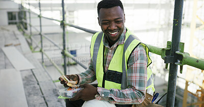 Buy stock photo Break, lunch and black man with smile at construction site, industrial infrastructure and nutrition. Sandwich, scaffolding and worker with food for meal time, hungry and relax on building foundation