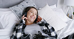 Woman, relax and laughing on bed with headphones, funny podcast or listening to online broadcast. Happy, female person and chill in home with audio tech, streaming service or radio comedy on weekend.