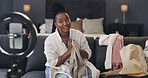 Influencer, ring light and black woman with clothes in home for live streaming, product review and opinion. Content creator, bedroom and person with fashion advice, feedback and talking on broadcast