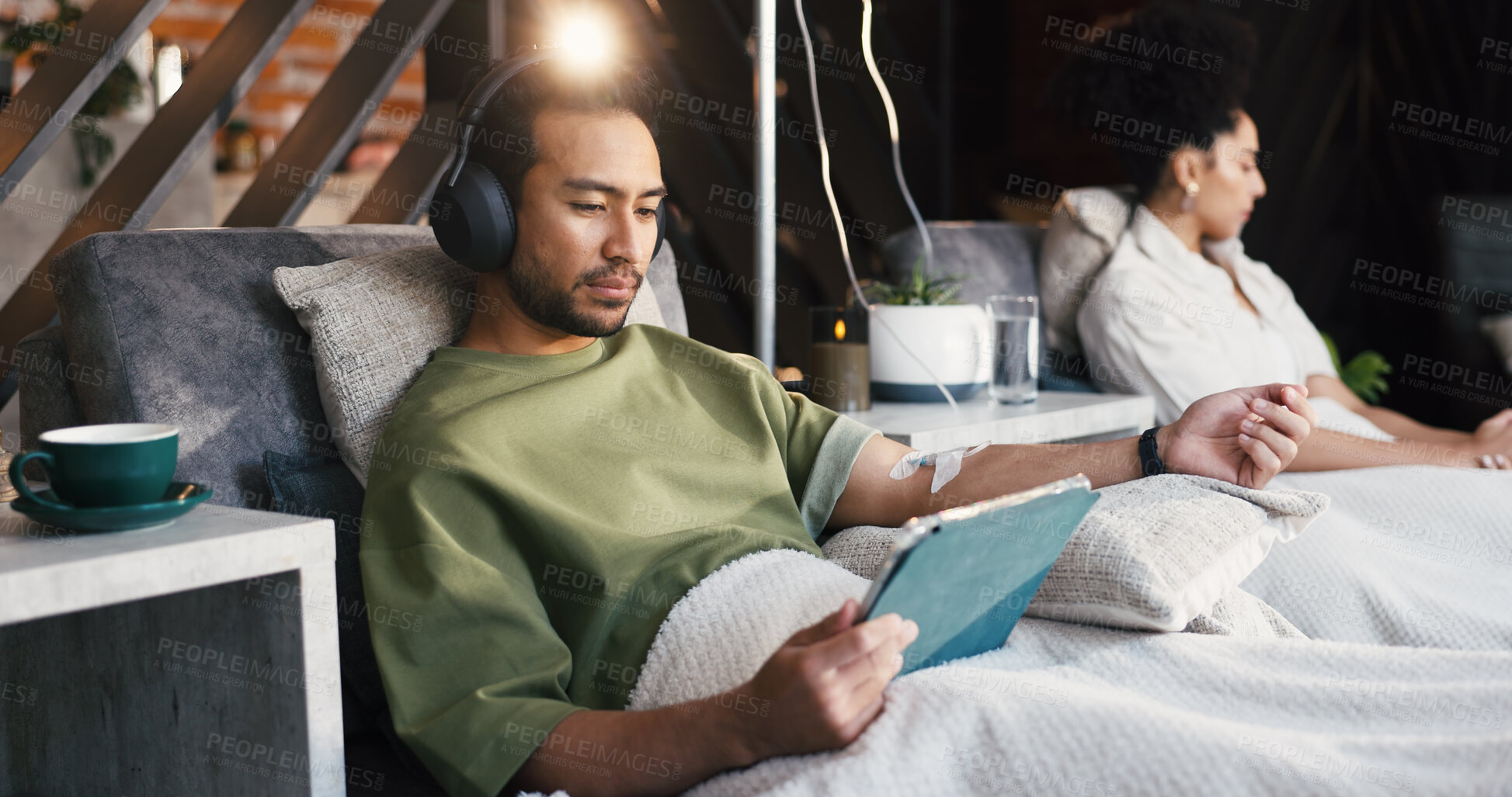 Buy stock photo Headphones, man and tablet with drip therapy in lounge for nutrients, recovery or streaming app. Flare, patient and tech with IV vitamin c for health benefits, mineral infusion or immune system boost