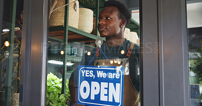 Buy stock photo Black man, open sign and thinking in nursery for sustainable business, botany and eco friendly startup. Botanist, door and board in plant store for operating hours, service announcement and pride