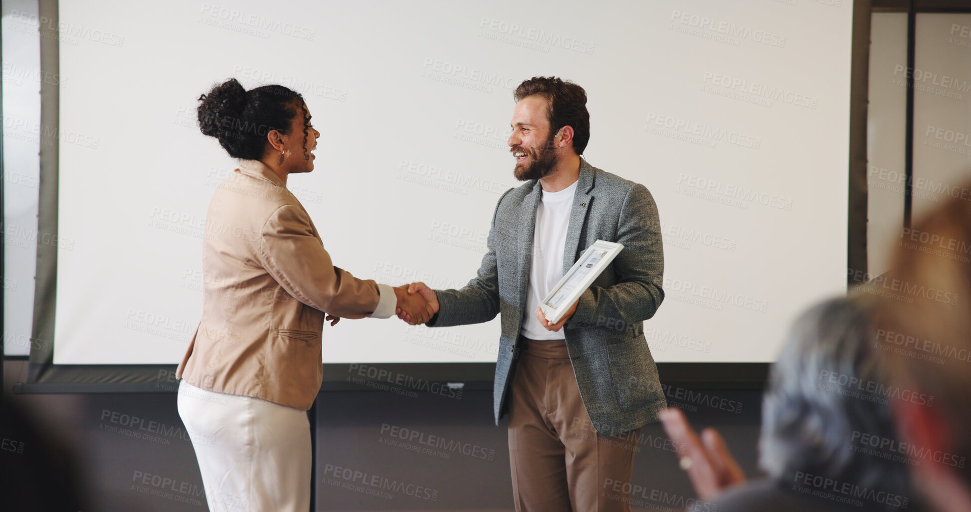 Buy stock photo Handshake, audience and speaker with award for presentation, business conference or event. People, shaking hands and prize announcement for workshop, achievement or recognition and career development