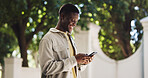 Black man, walking and smile outdoor with smartphone for communication or social media. Happy male person, typing on mobile phone and contact with texting, message or email in nature with chat app