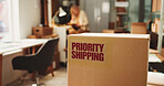 Label, logistics and box in office for distribution with priority shipping for freight delivery. Sticker, cardboard package and ecommerce parcel with express service for cargo, supply chain or export