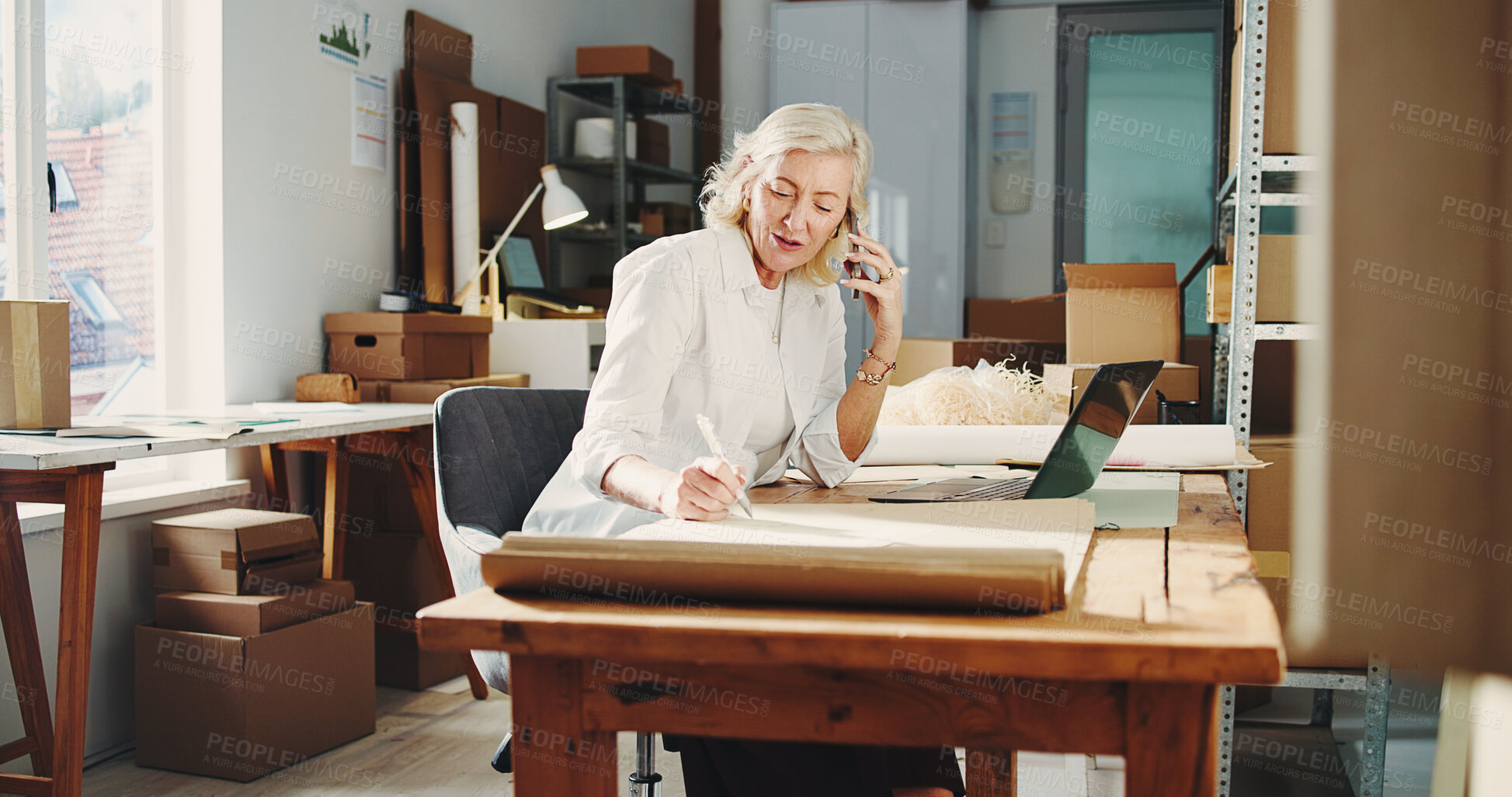 Buy stock photo Logistics, phone call or woman in office with writing, track delivery or inventory management of shipment. Distribution, mature person or supplier with tech, order update or checklist in ecommerce.