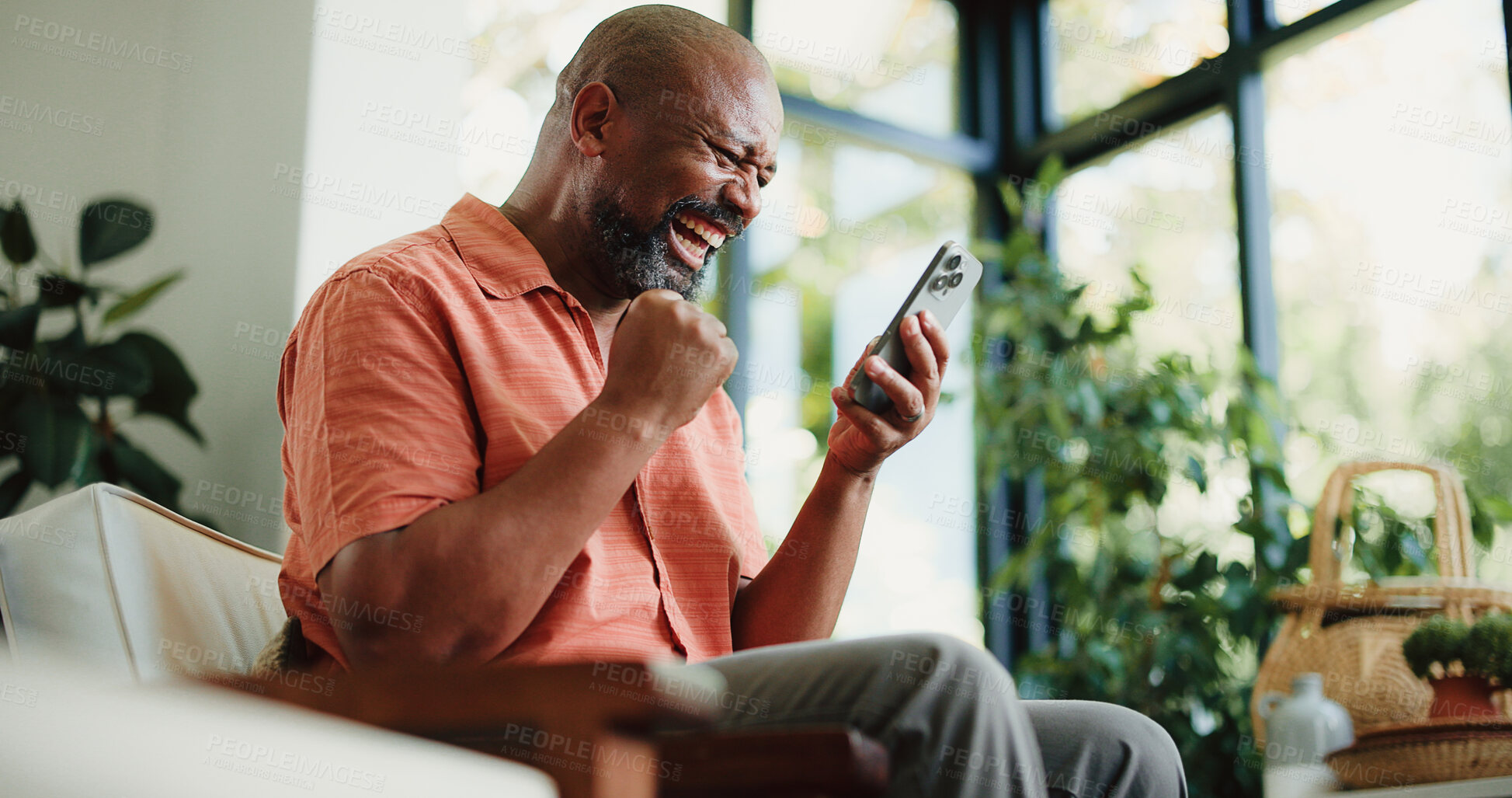 Buy stock photo Man, excited or fist pump with phone in home for online notification, gambling success or achievement. Mature black person, happy or celebration in house with tech, betting win and competition prize.
