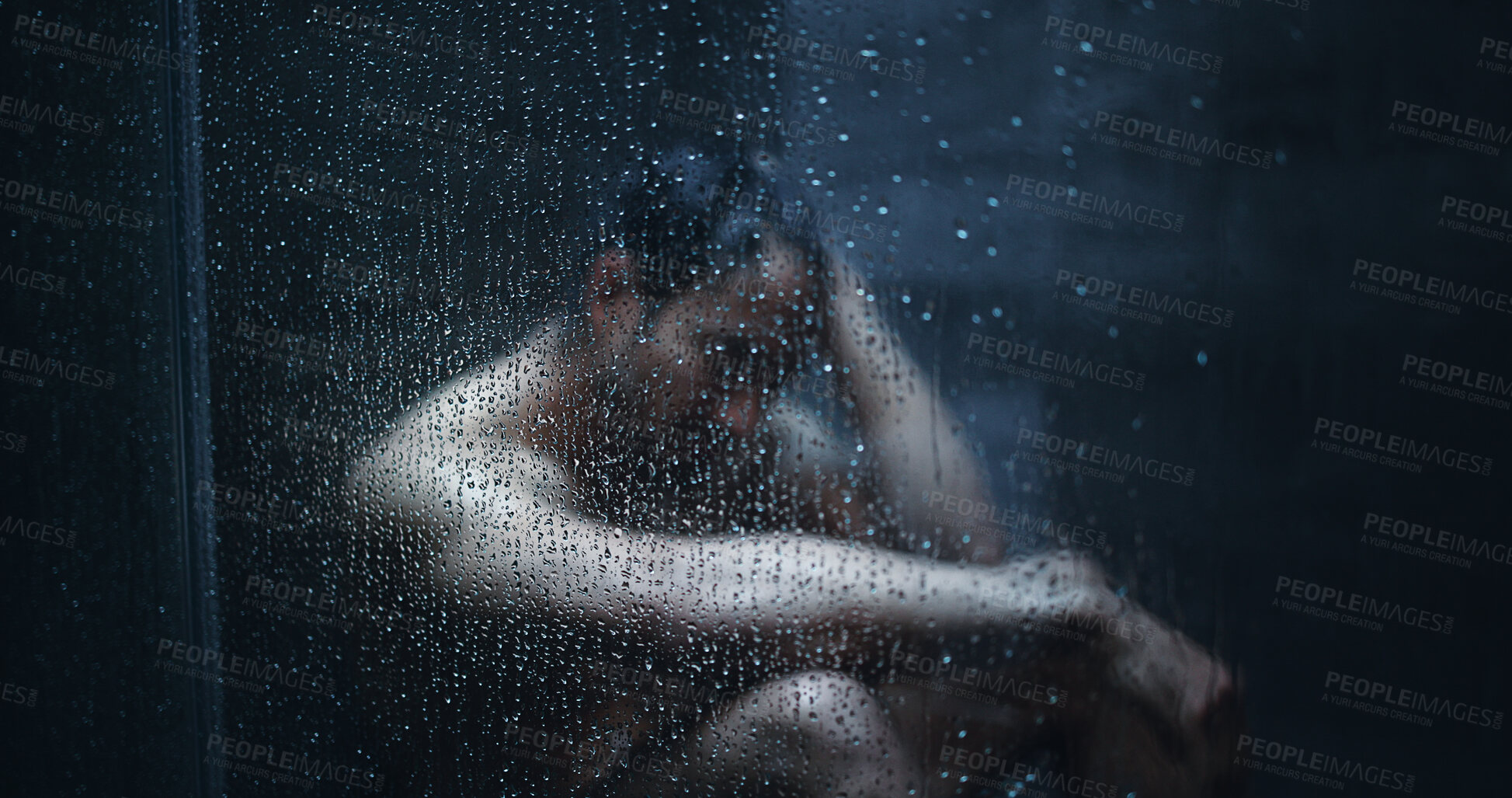 Buy stock photo Man, shower and droplets in bathroom for mental health, reflection or thinking in home. Person with depression, house and running water for fear, grief and glass with anxiety, doubt or stress