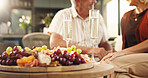 Elderly couple, champagne glasses and fruit with romance for anniversary date in home. Senior, man and woman with charcuterie board, alcohol or healthy food for valentines day together in house