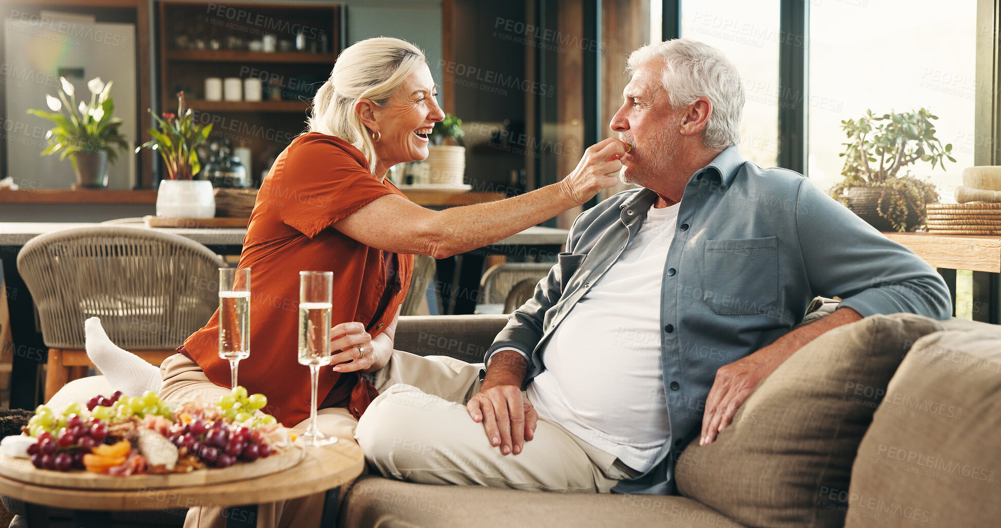 Buy stock photo Anniversary, celebration and senior couple on couch for romantic date, affection or marriage commitment. Home, loyalty or old people with charcuterie board for special day, happiness or feeding fruit