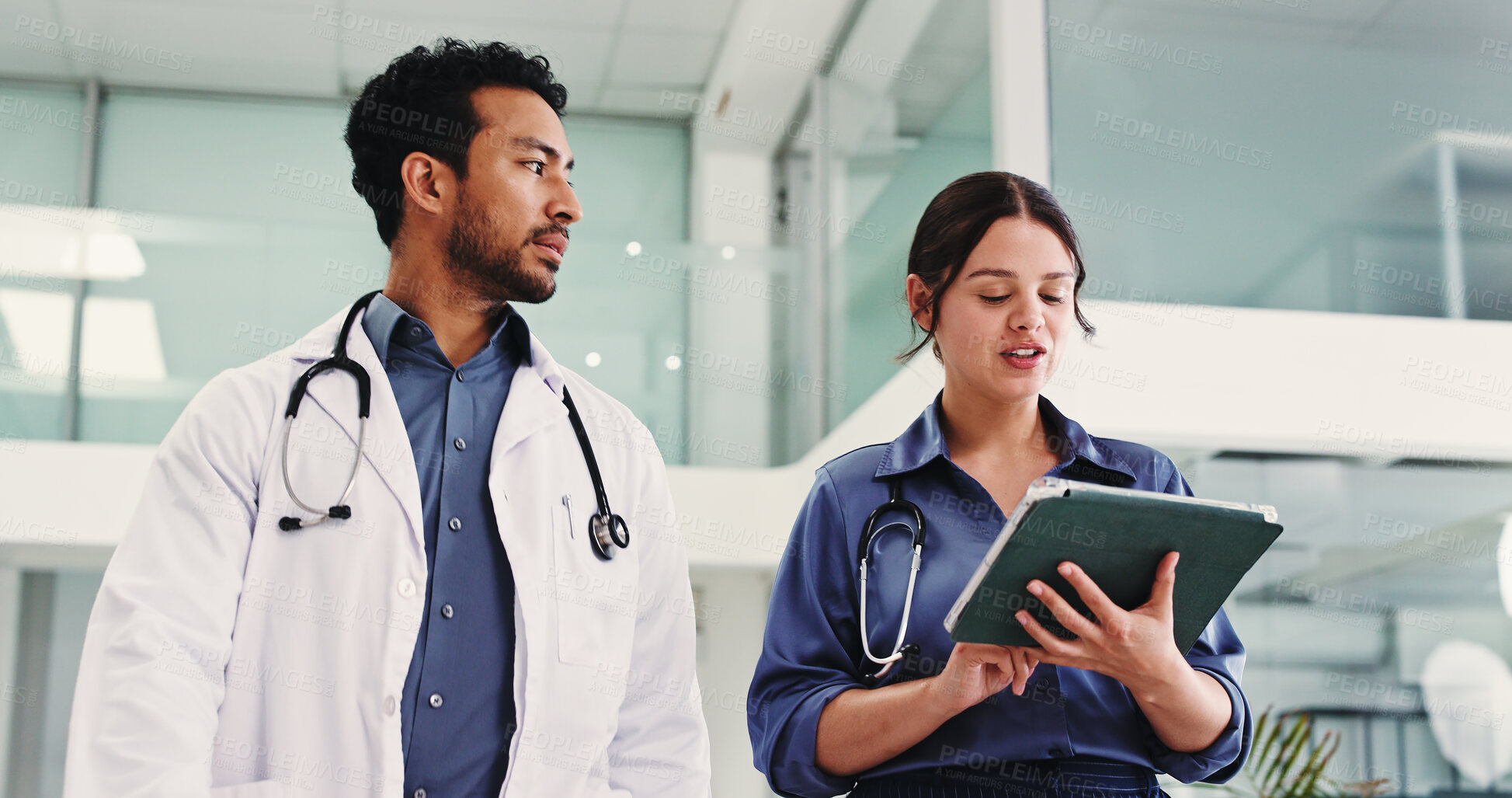 Buy stock photo Doctors, talk and tablet in lobby with team, review and check schedule for healthcare services at clinic. People, medical staff and tech with application, low angle and walk in hallway at hospital