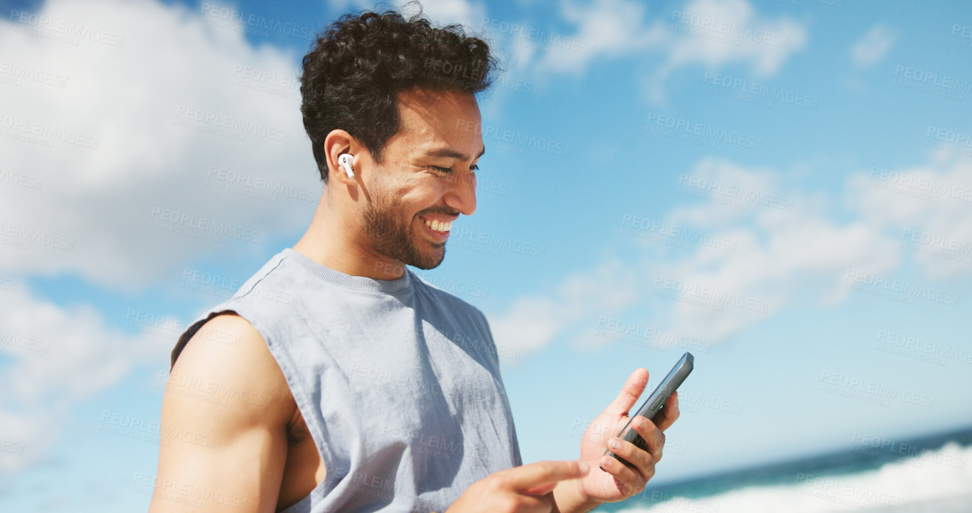 Buy stock photo Beach, below and happy man with fitness, smartphone and online reading for text message. Ocean, cellphone and person with smile, social media and digital app to track progress, internet and exercise
