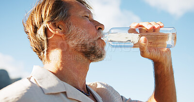 Buy stock photo Below, mature man and drinking water for fitness outdoor for hydration, nutrition and exercise break. Male person, thirsty and bottle with refreshing beverage, liquid mineral and recovery of training