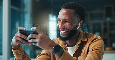 Buy stock photo Gaming, smartphone and man with earphones, home and listening to audio on break, laughing and online. Happy, gamer and black person with mobile for entertainment, esports and tech for sound in house
