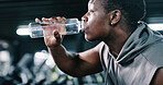Black man, fitness or drinking with water bottle in gym for hydration, recovery or workout break. Active, male person or mineral liquid with thirst for exercise, rest or sustainability in health club