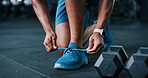 Person, hands and tying with shoes in gym for workout preparation, exercise or indoor training. Closeup, active or runner getting ready with sneakers, laces or dumbbells for fitness in health club
