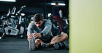 Man, fitness or stretching with leg in gym for workout preparation, exercise or indoor training. Active, male person or getting ready with warm up or dumbbells on space for flexibility in health club