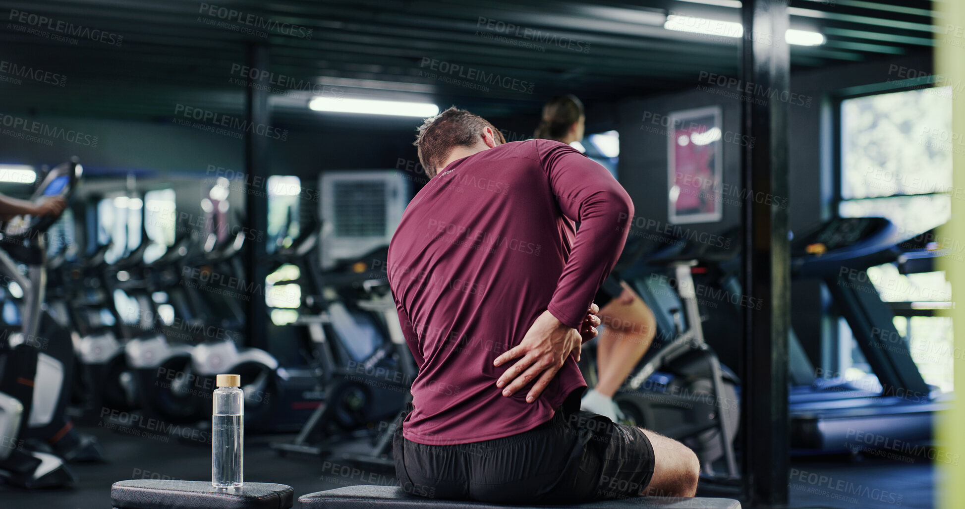 Buy stock photo Active, back pain and exercise with man in gym for training accident or workout mistake. Fitness, space and spine injury with person in health club for condition, inflammation or muscle fatigue