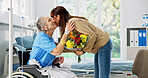 Hospital, flowers and woman with elderly mother for support, comforting and gift for surgery recovery. Healthcare, wheelchair and person with bouquet for senior patient for healing, wellness and love