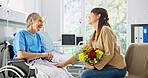 Hospital, flowers and woman with mother in wheelchair for support, comforting and gift for surgery recovery. Healthcare, family and person with bouquet for elderly mom for healing, wellness and love