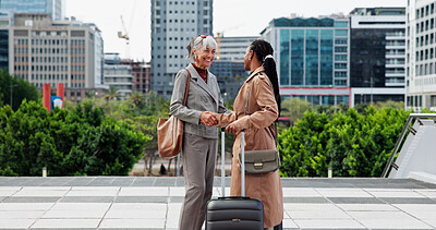 Buy stock photo Happy, business women and meeting with handshake in city for work trip, commute or partnership. Female people, employees or colleagues shaking hands with smile or suitcase for travel or deal in town
