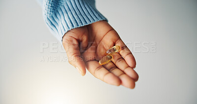 Buy stock photo Hand, pills and person with medicine in studio for health, wellness or sickness recovery. Pharmaceutical, immune booster and model with capsules for vitamins, tablets or medication by gray background