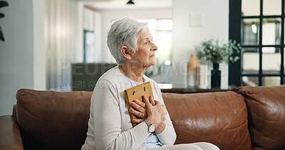 Buy stock photo Photograph, sad and thinking with old woman on sofa in living room of home for grief, loss or pain. Picture frame, reflection and senior person with depression in apartment for memories or nostalgia