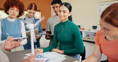 Buy stock photo Windmill, students and communication in classroom for education, science lesson and explain wind power. Learning, people and teenagers writing notes for knowledge, clean energy and turbine mechanics